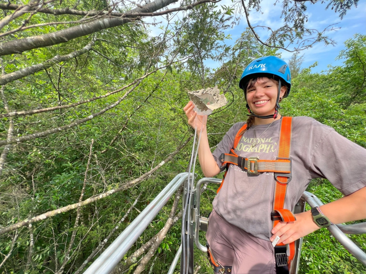 Photo shows Hannah Burrows (HU '26) with a methane measuring device at Harvard Forest