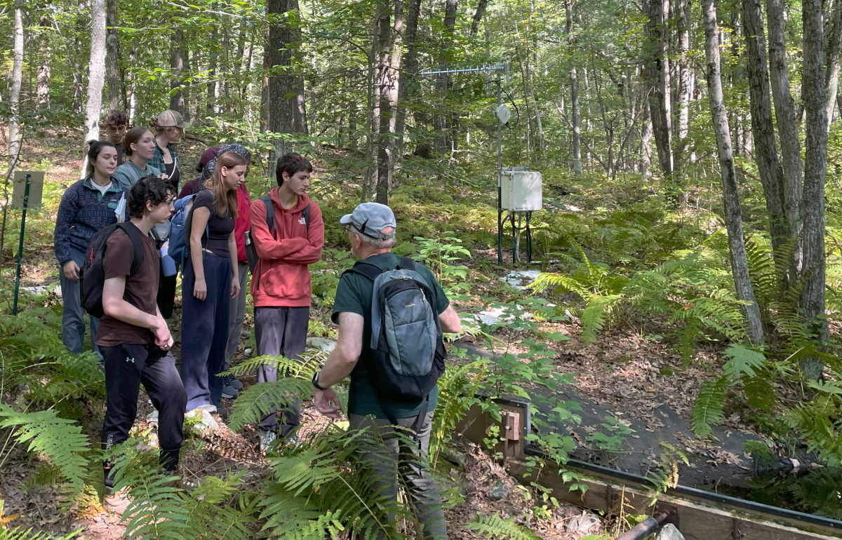 [<i>Image shows students in Orwig's 2024 First-Year Seminar class outside in the woods, learning about hydrologic research from Emery Boose (Harvard Forest Senior Scientist and Information Manager). </i>]